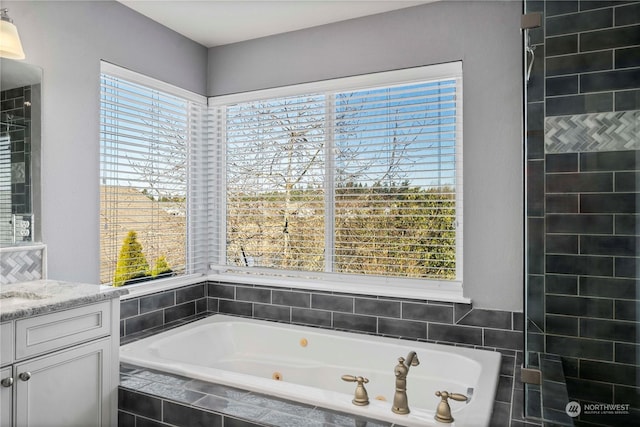 bathroom featuring vanity, tiled bath, and a healthy amount of sunlight