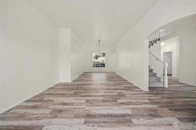 interior space with an inviting chandelier, a towering ceiling, and wood-type flooring