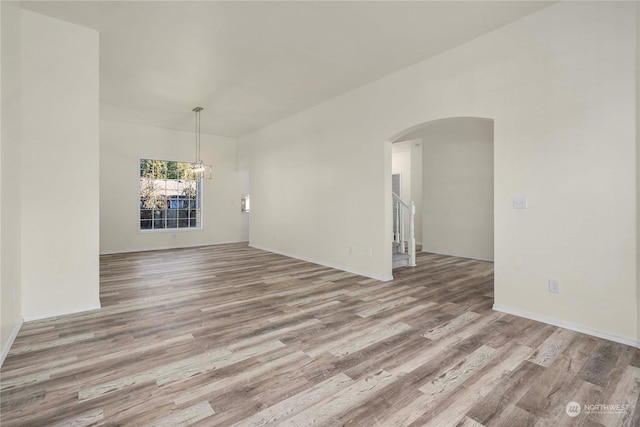 empty room featuring an inviting chandelier and light wood-type flooring