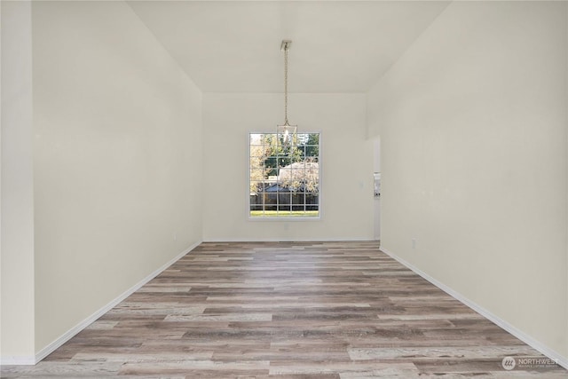 unfurnished dining area featuring light hardwood / wood-style floors and a chandelier