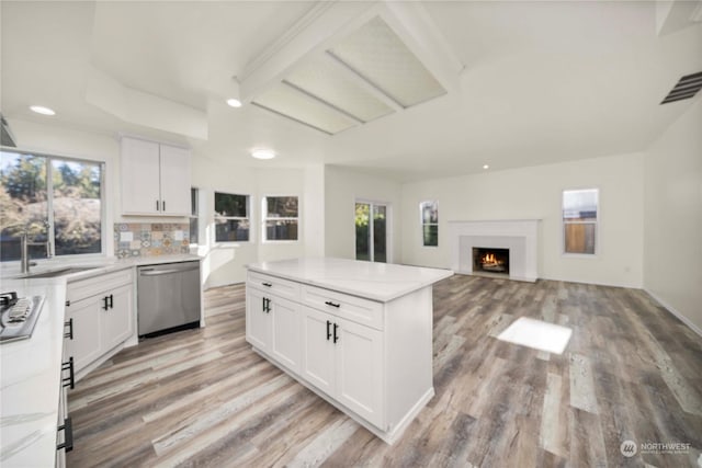 kitchen with light wood-type flooring, dishwasher, sink, and white cabinets