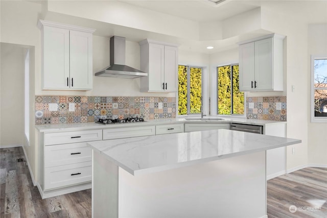 kitchen featuring a kitchen island, sink, white cabinets, and wall chimney exhaust hood