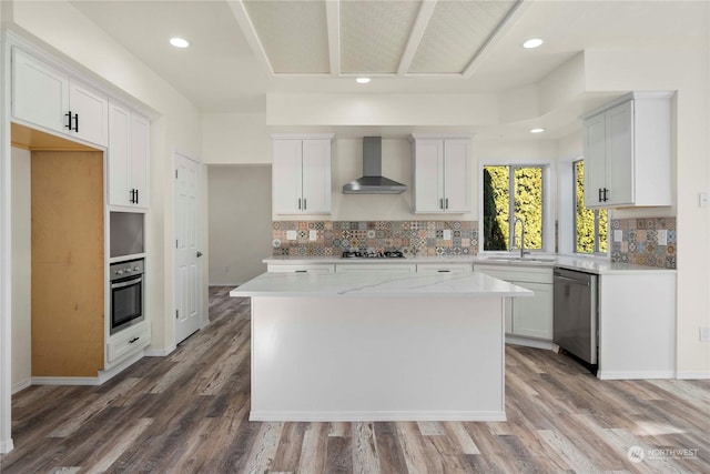 kitchen with a kitchen island, appliances with stainless steel finishes, sink, white cabinets, and wall chimney range hood