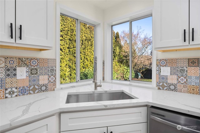 kitchen featuring sink, stainless steel dishwasher, white cabinets, and light stone countertops