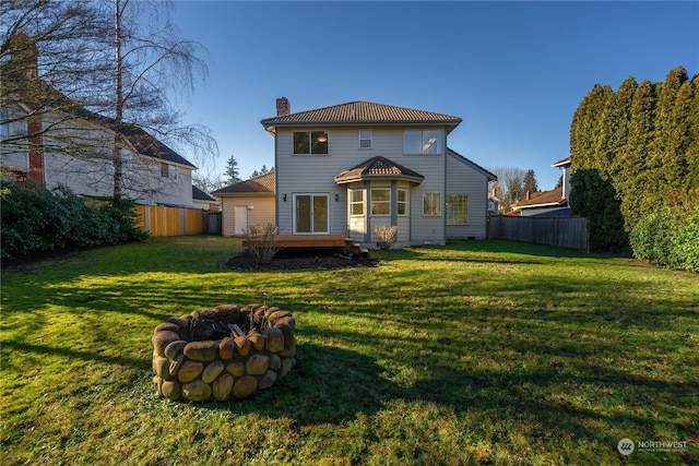 rear view of house with a wooden deck, a lawn, and an outdoor fire pit