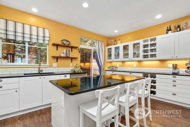 kitchen with a breakfast bar area, sink, a kitchen island, and white cabinets