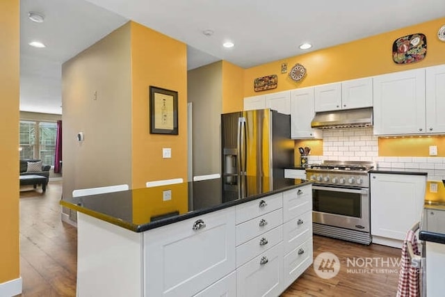 kitchen featuring appliances with stainless steel finishes, white cabinets, backsplash, hardwood / wood-style flooring, and a center island