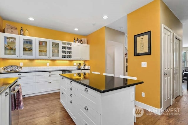 kitchen featuring hardwood / wood-style flooring, a kitchen island, stainless steel dishwasher, and white cabinets