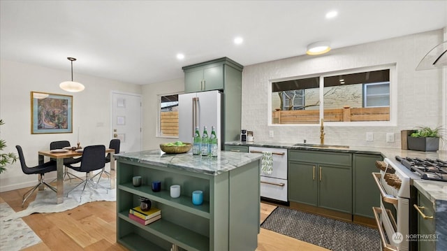 kitchen featuring a kitchen island, sink, premium appliances, hanging light fixtures, and green cabinetry