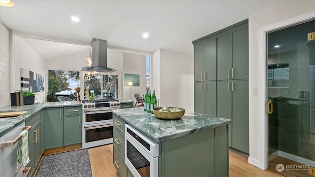 kitchen featuring island exhaust hood, green cabinetry, a kitchen island, built in microwave, and range with two ovens