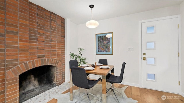 dining space with hardwood / wood-style flooring and a fireplace