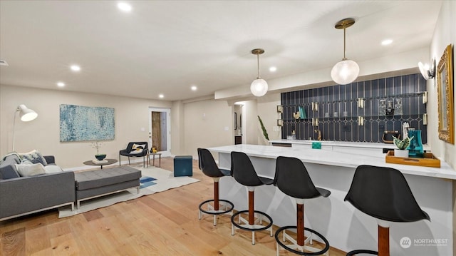 kitchen featuring light stone counters, decorative light fixtures, light hardwood / wood-style floors, and kitchen peninsula