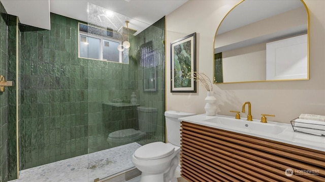 bathroom with a tile shower, vanity, and toilet