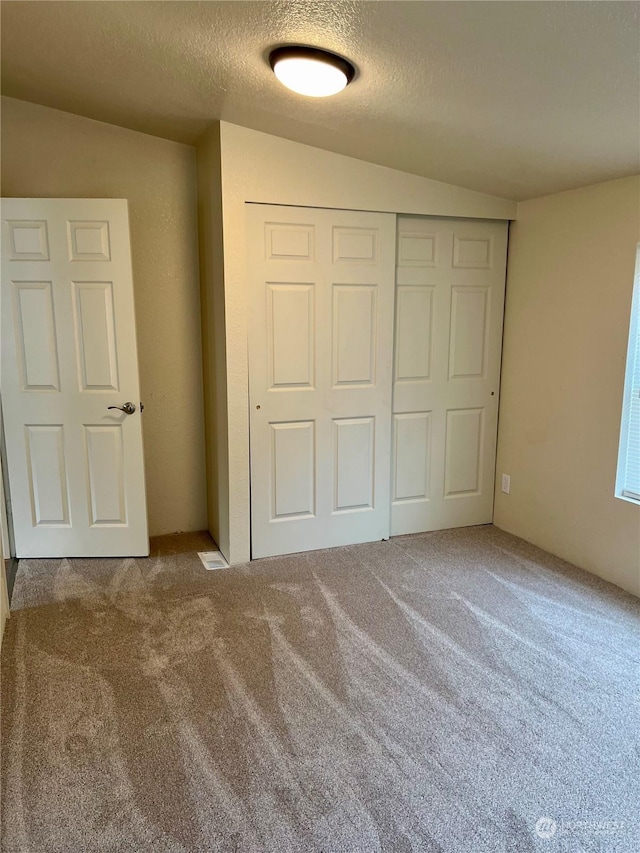 unfurnished bedroom featuring carpet, a textured ceiling, and a closet