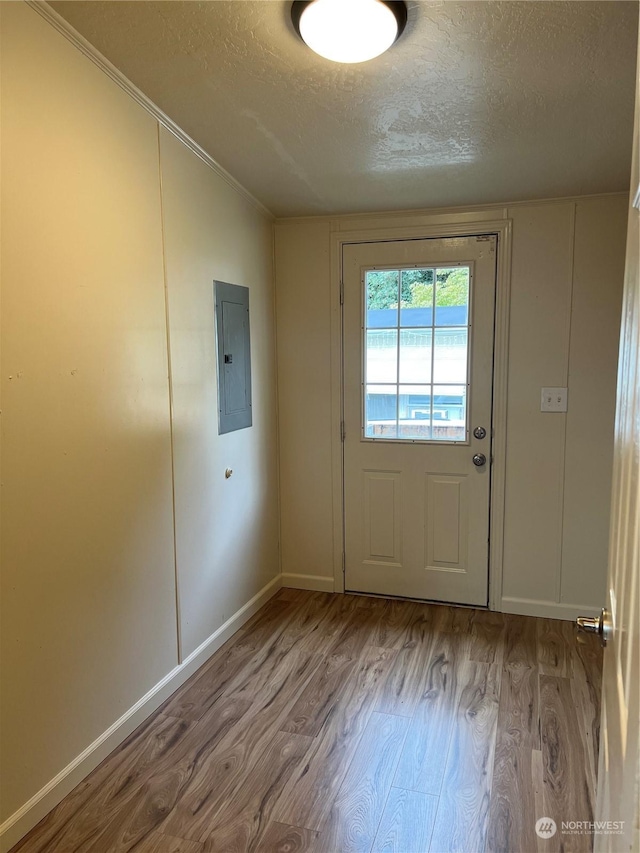 doorway featuring electric panel, light hardwood / wood-style floors, and a textured ceiling