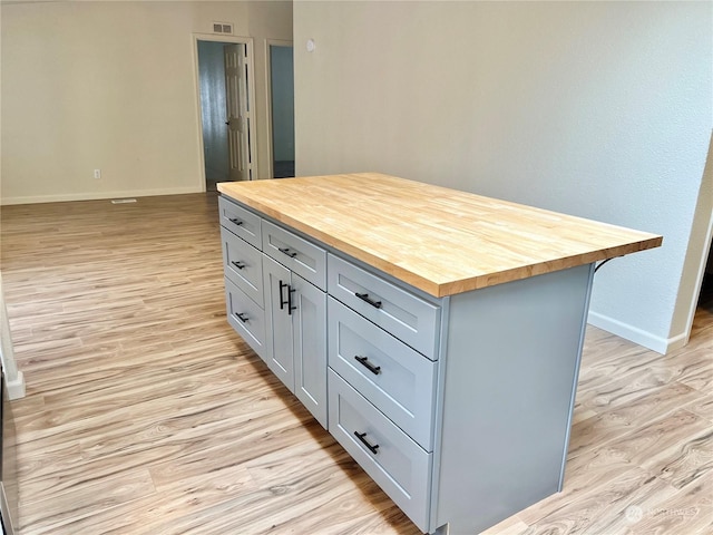 kitchen featuring gray cabinets, a kitchen island, wooden counters, and light wood-type flooring