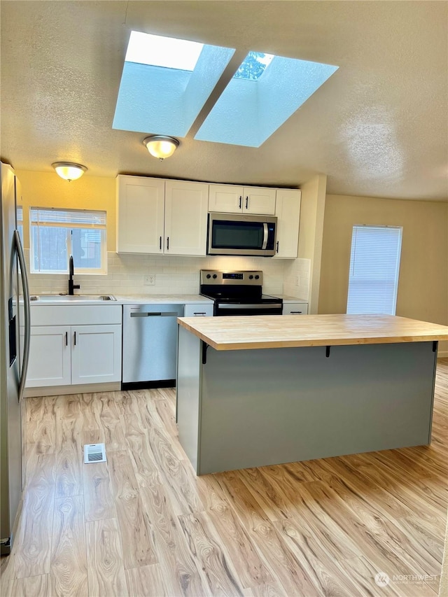 kitchen with white cabinetry, sink, stainless steel appliances, and light wood-type flooring