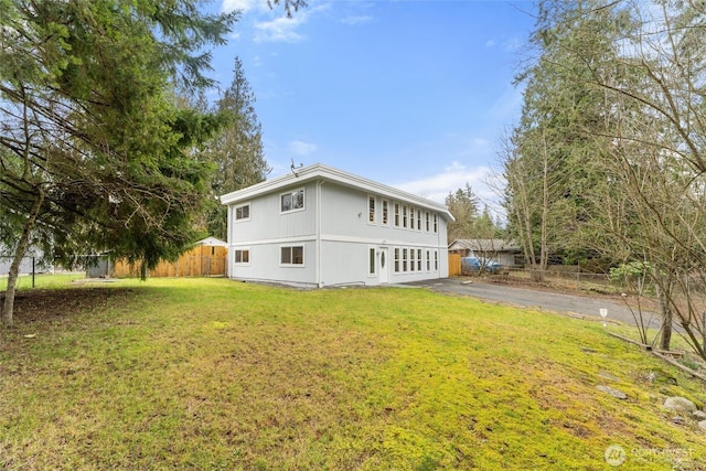 back of property featuring fence and a lawn