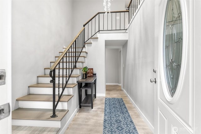 entrance foyer featuring a towering ceiling, stairway, baseboards, and wood finished floors