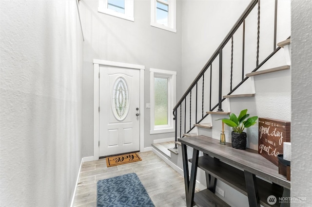 foyer entrance with stairs, baseboards, and wood finish floors