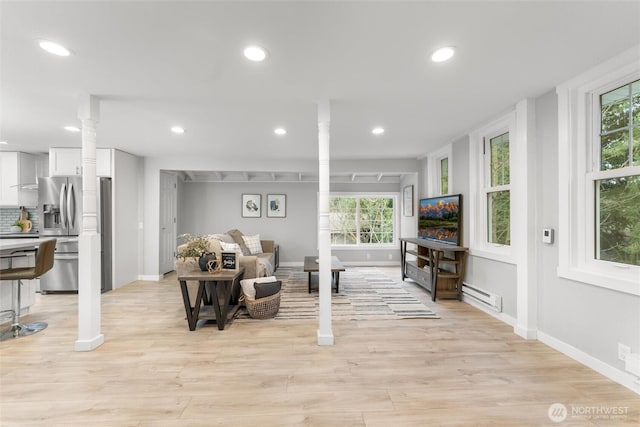 interior space featuring light wood-type flooring, ornate columns, a baseboard radiator, and recessed lighting