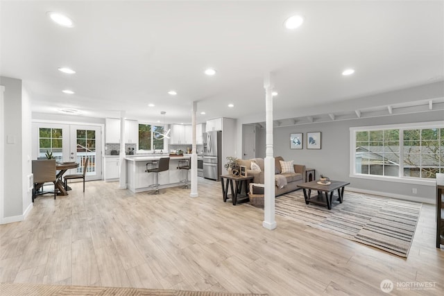 living area with light wood-style floors, recessed lighting, and french doors