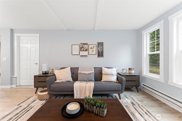 living room with a baseboard heating unit, light wood finished floors, beamed ceiling, and baseboards