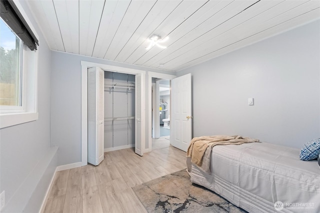 bedroom featuring light wood finished floors, a closet, wood ceiling, and baseboards