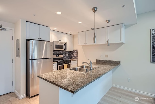 kitchen with white cabinetry, appliances with stainless steel finishes, decorative light fixtures, and kitchen peninsula