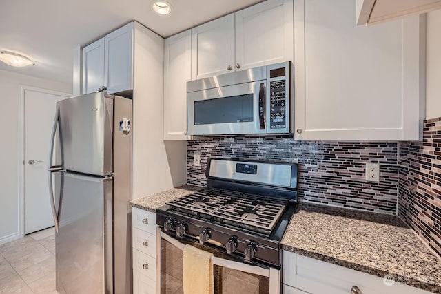 kitchen featuring white cabinetry, appliances with stainless steel finishes, backsplash, and dark stone counters