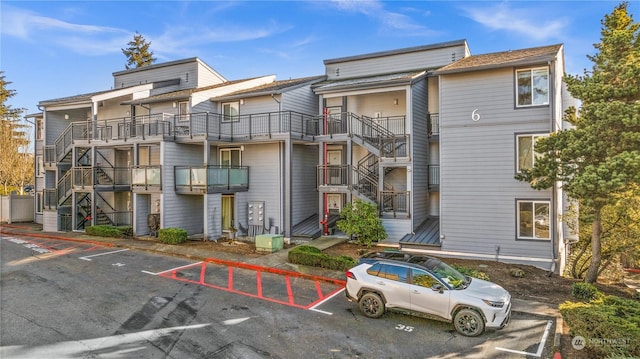 view of building exterior featuring stairway and uncovered parking