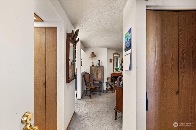 corridor featuring light colored carpet and a textured ceiling