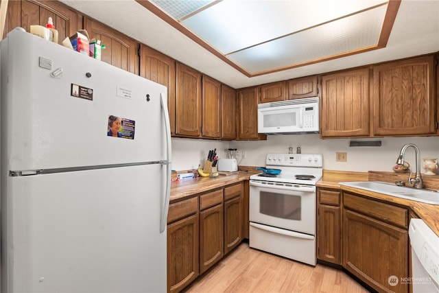 kitchen featuring sink, white appliances, and light wood-type flooring