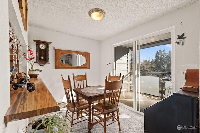 dining room featuring light colored carpet and a textured ceiling