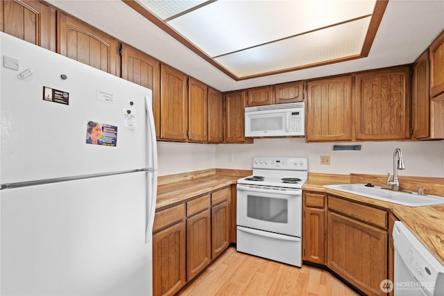 kitchen with brown cabinets, white appliances, and a sink