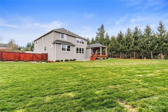 rear view of house with a wooden deck and a lawn