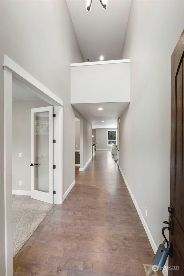 hall featuring a towering ceiling and hardwood / wood-style floors