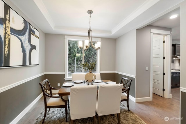 dining room featuring dark wood-type flooring, a tray ceiling, and a chandelier