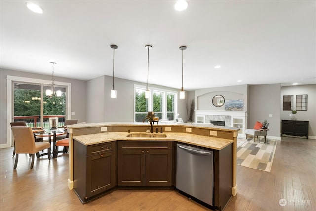 kitchen featuring pendant lighting, dishwasher, sink, dark brown cabinetry, and a center island with sink