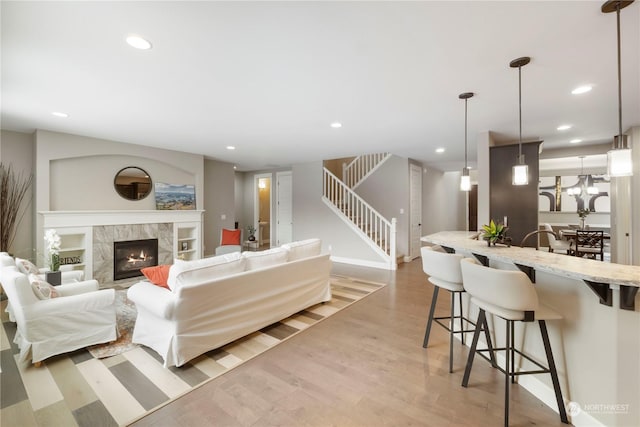 living room featuring a high end fireplace and light wood-type flooring