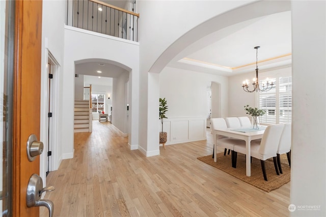 foyer entrance with a tray ceiling, light hardwood / wood-style floors, and a chandelier