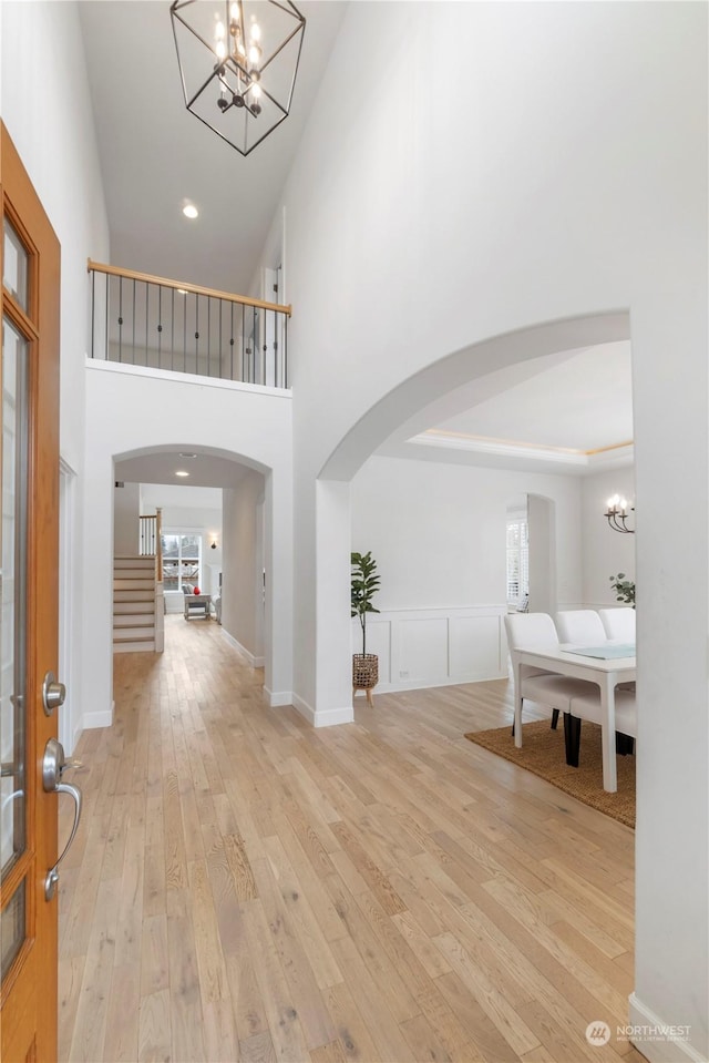 entryway with a high ceiling, a chandelier, and light hardwood / wood-style floors