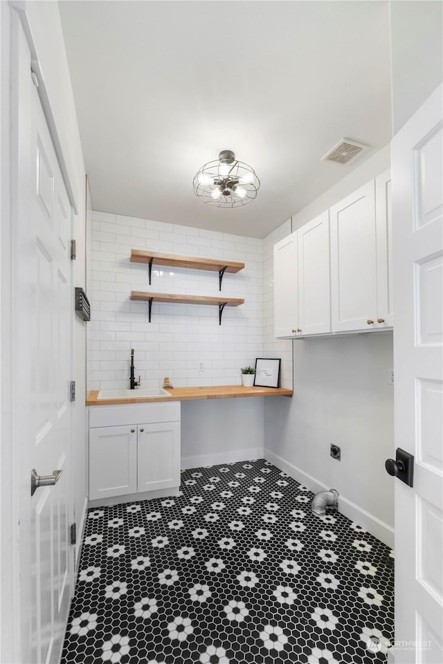 clothes washing area with cabinets and sink