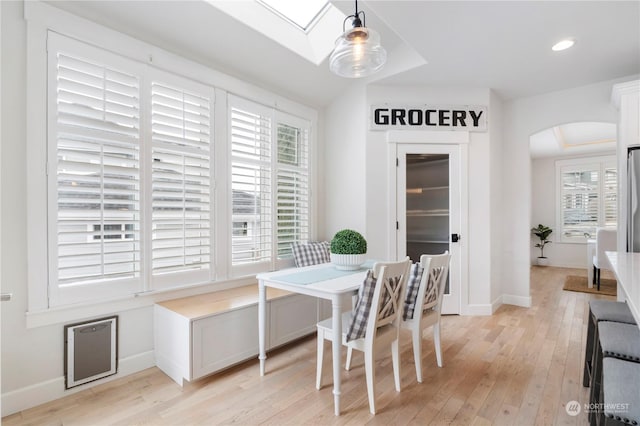 dining room with a healthy amount of sunlight, lofted ceiling with skylight, and light wood-type flooring