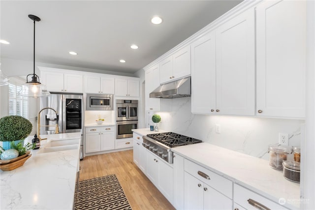 kitchen featuring decorative light fixtures, white cabinetry, sink, light stone counters, and stainless steel appliances