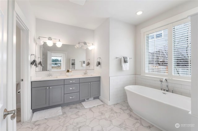 bathroom with vanity, tile walls, and a tub