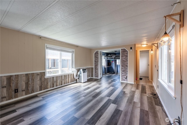 unfurnished room featuring hardwood / wood-style floors, a textured ceiling, and wood walls