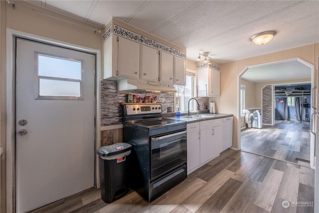 kitchen featuring sink, electric range oven, white cabinets, light hardwood / wood-style floors, and backsplash