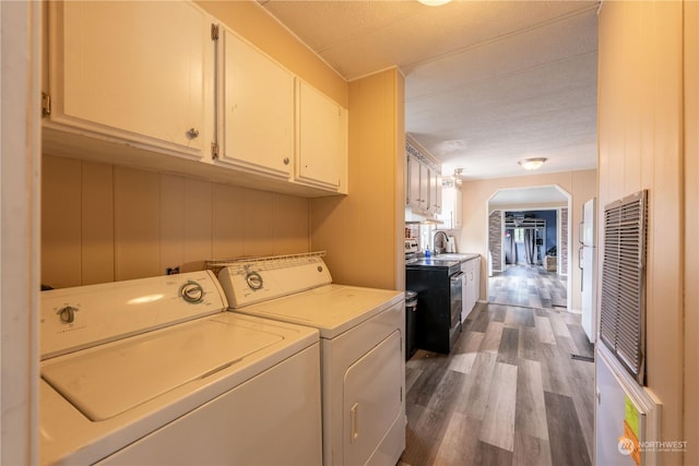 washroom with wooden walls, dark hardwood / wood-style floors, washer and clothes dryer, and sink