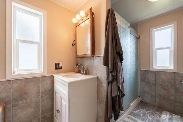 bathroom with vanity, a shower with shower door, and tile walls